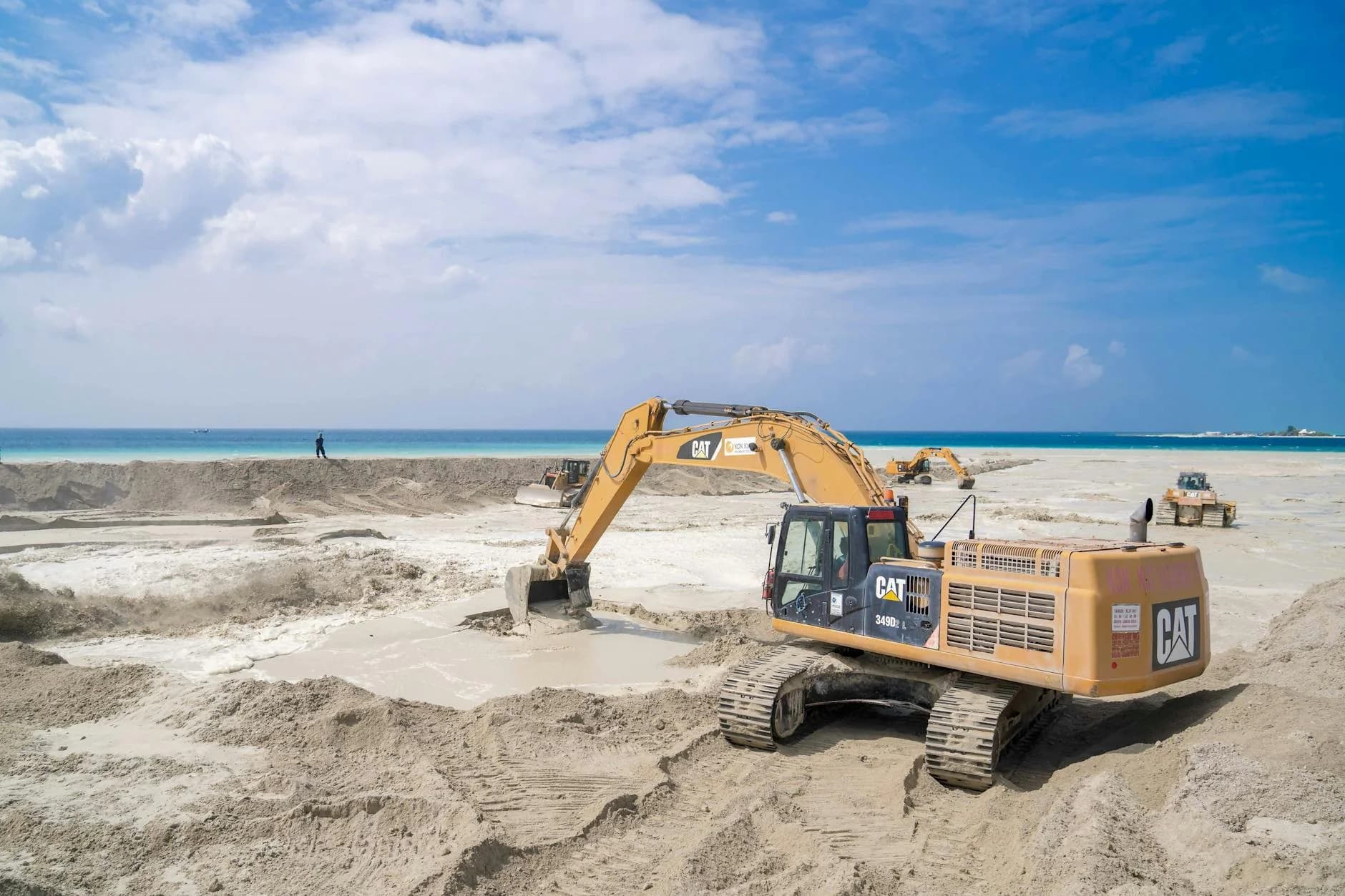 An Excavator Working On A Sandy Beach Co 1