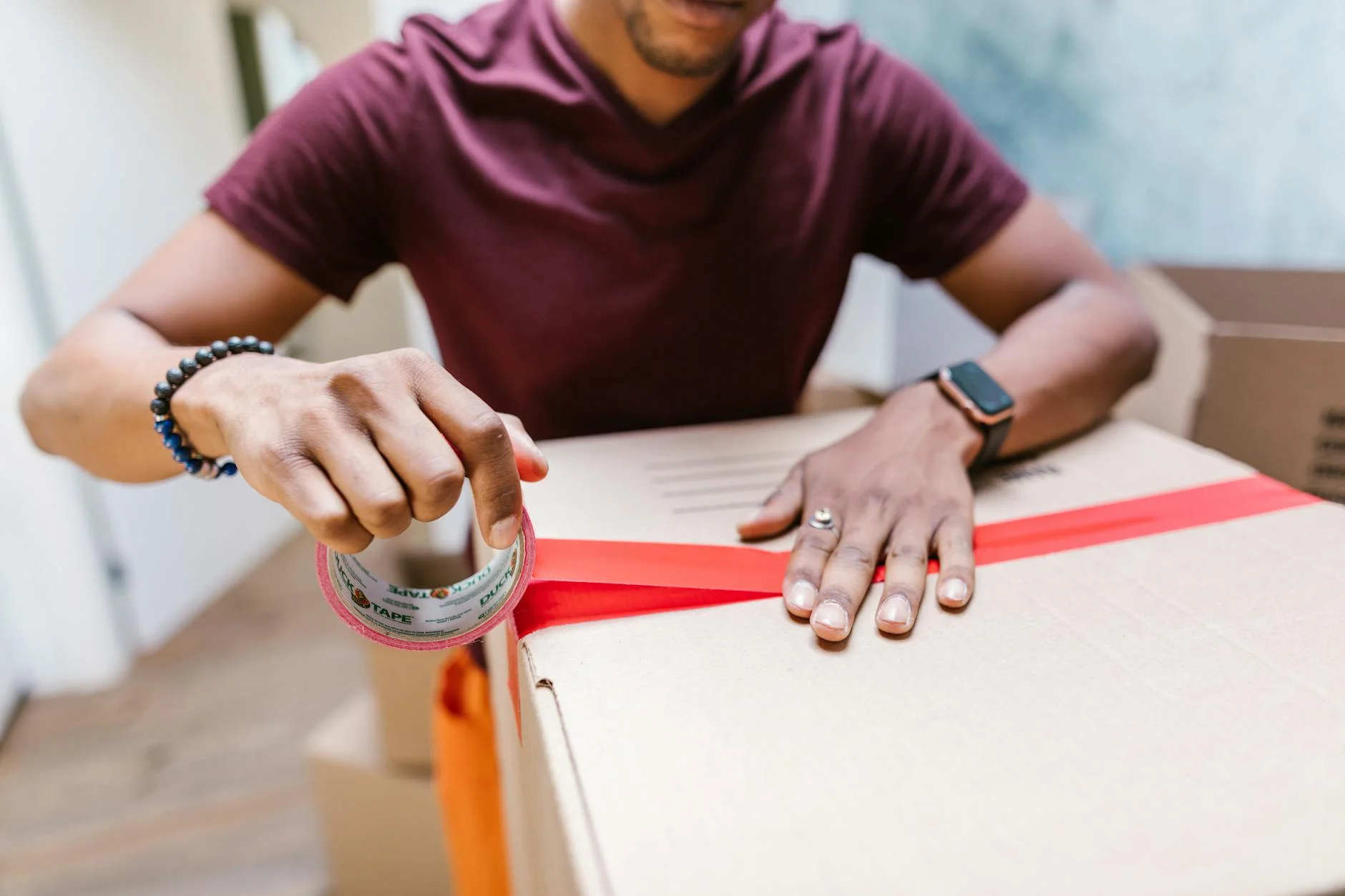 A Man Applying Tape To A Cardboard Box F 1
