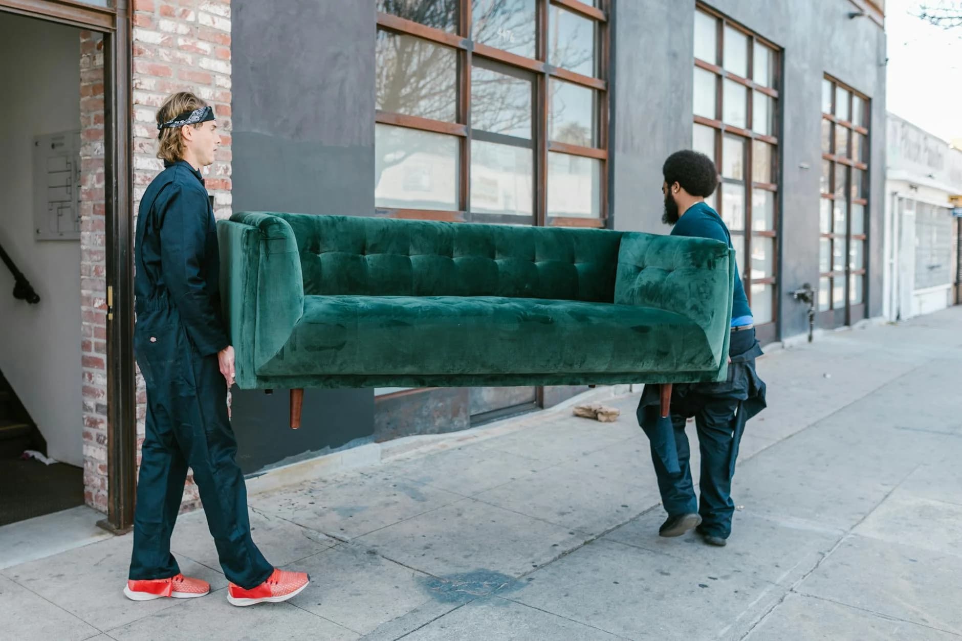 Two Men Carrying A Green Sofa On A City 1