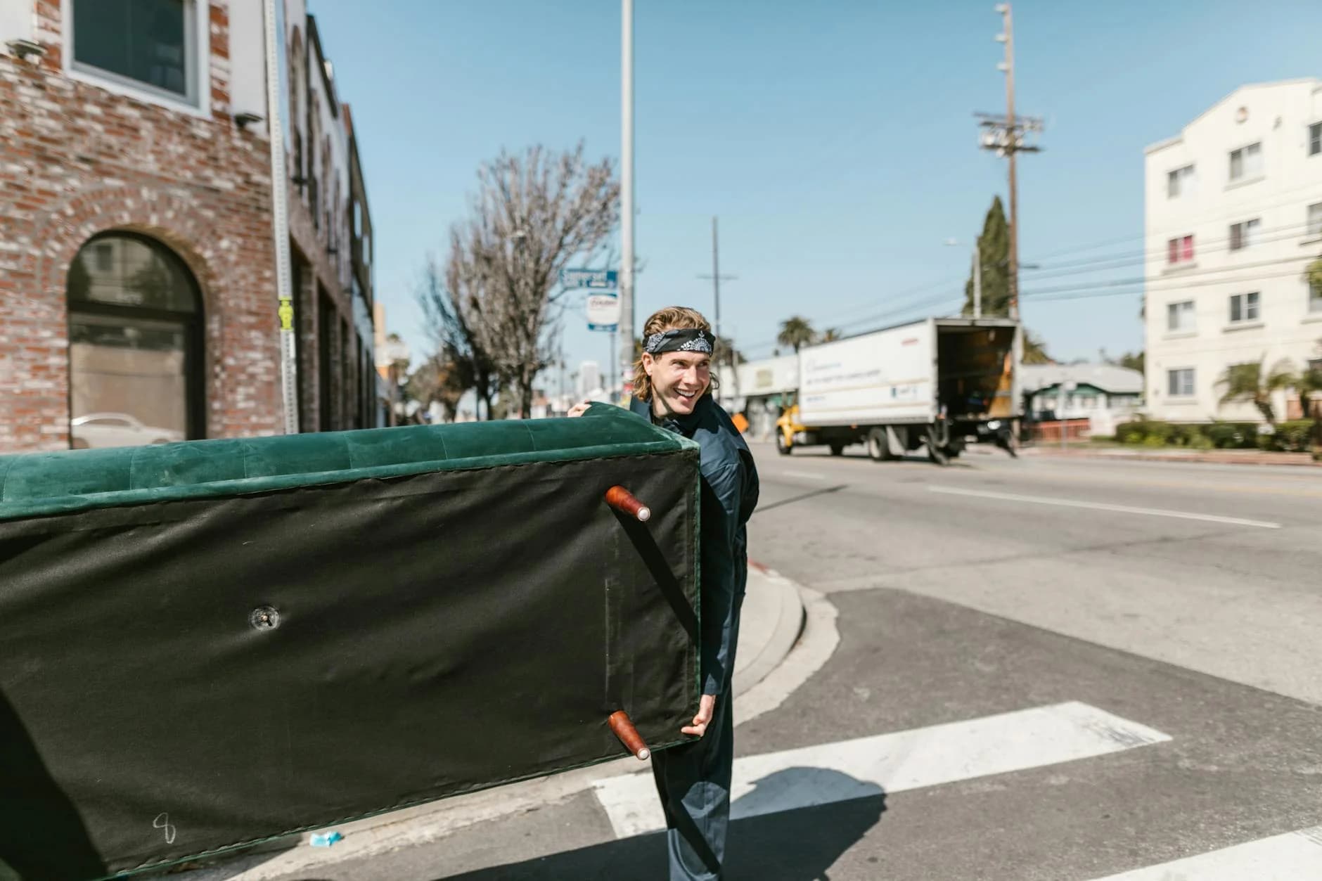 A Cheerful Man Carries A Large Couch Acr 1
