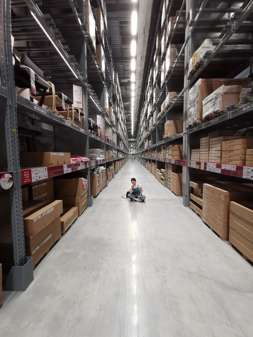 An Asian Woman Sits In A Large Warehouse 2