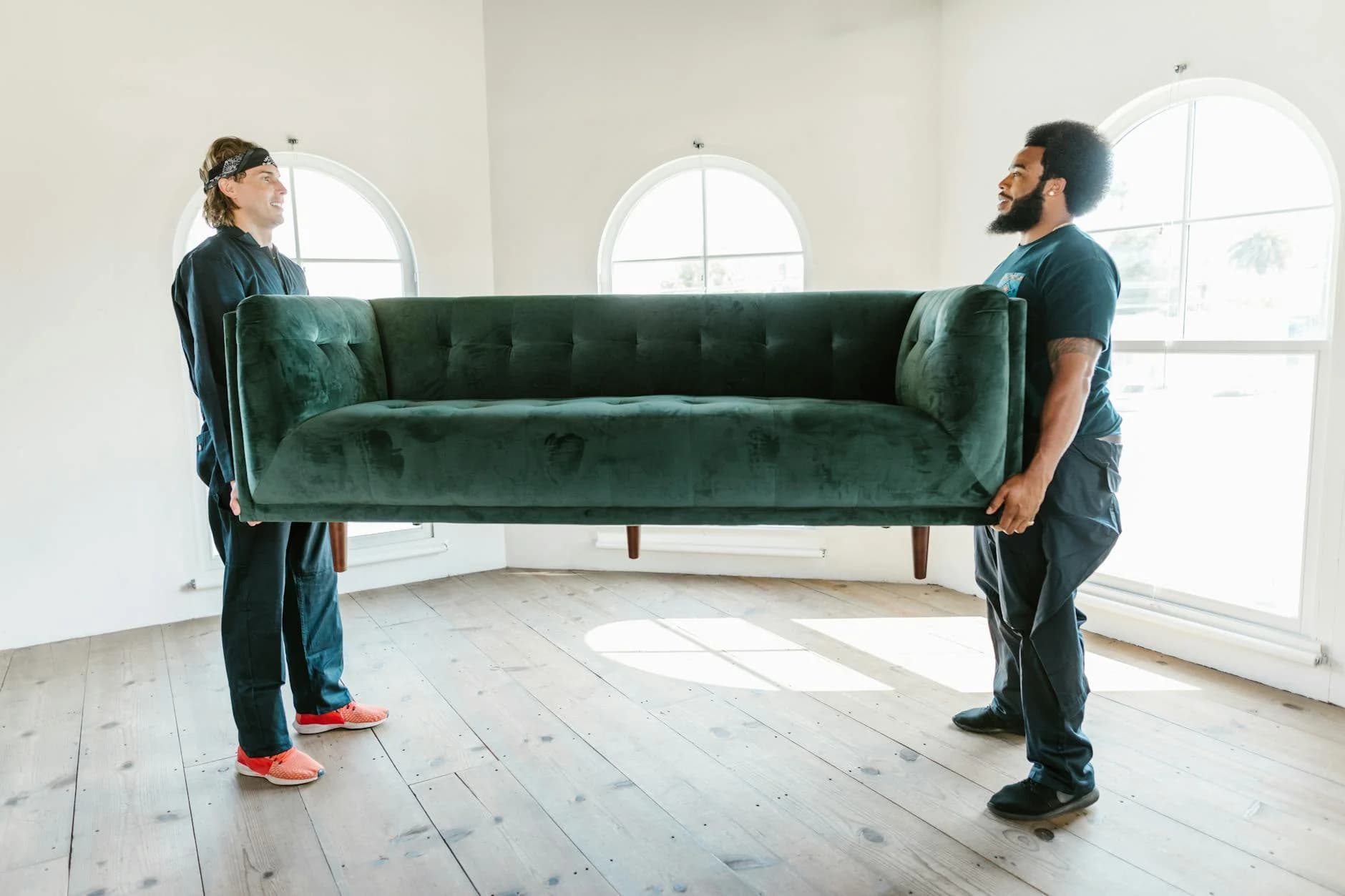 Two Men Lifting A Green Sofa In A Well L 2