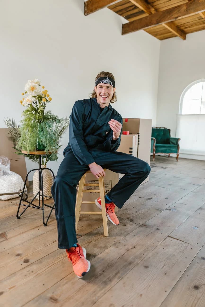 Man Sitting On A Stool In A Room With Mo 1