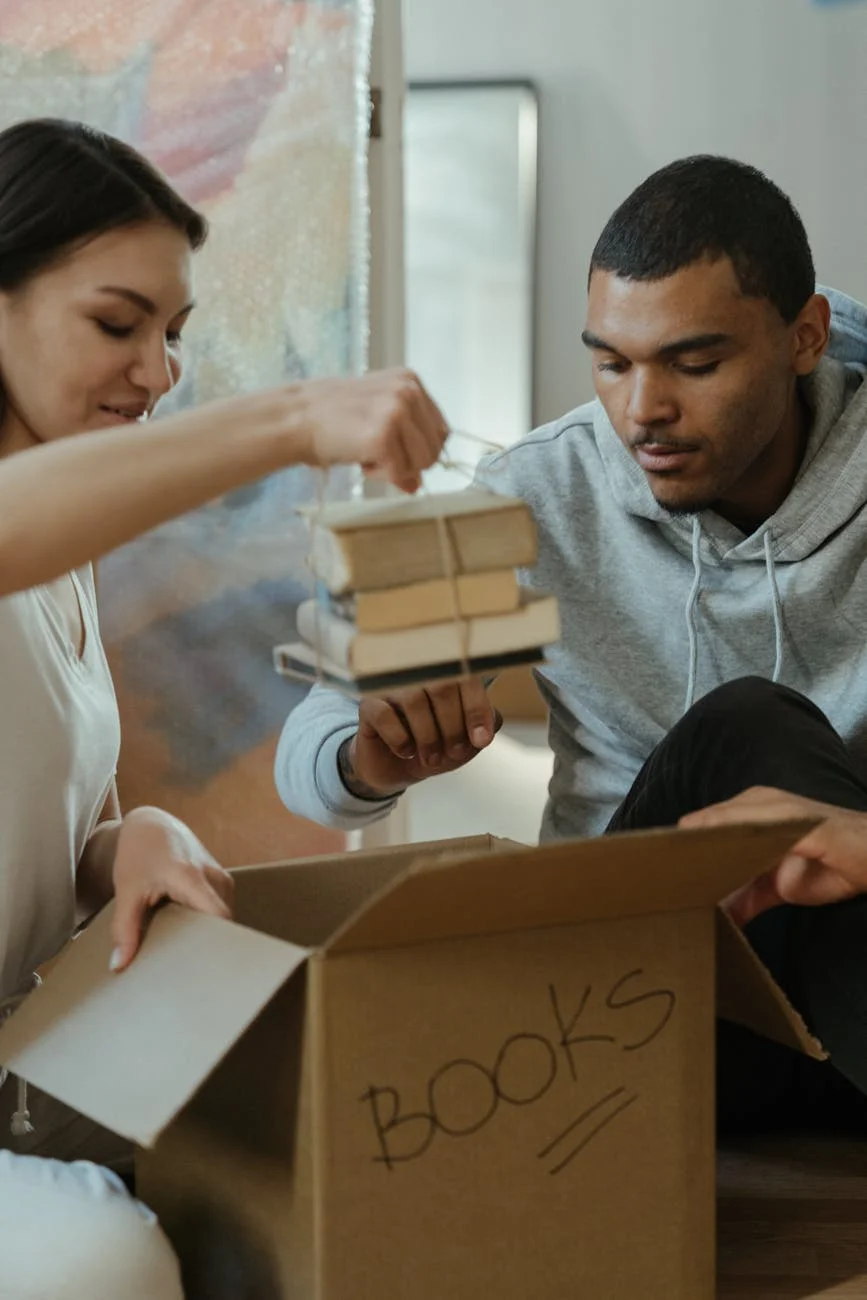 A Young Couple Unpacking Books In Their 4