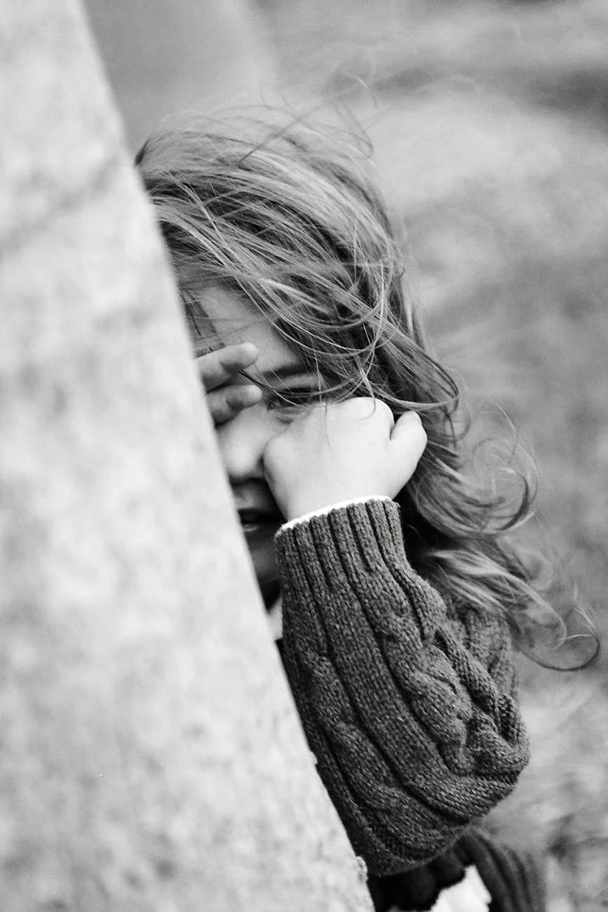 A Young Child Playfully Hides Behind A T 2