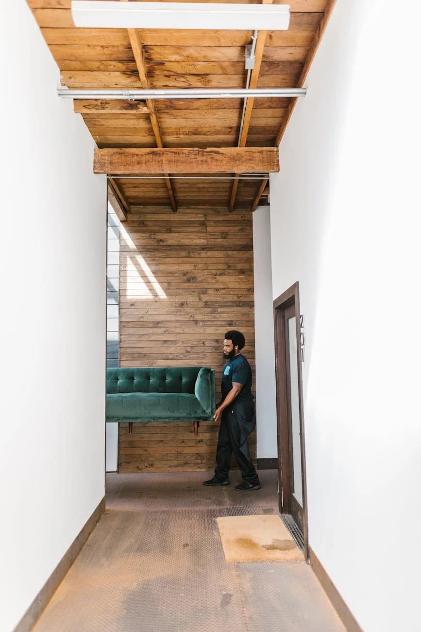 A Man With Afro Hair Moves A Teal Sofa T 4